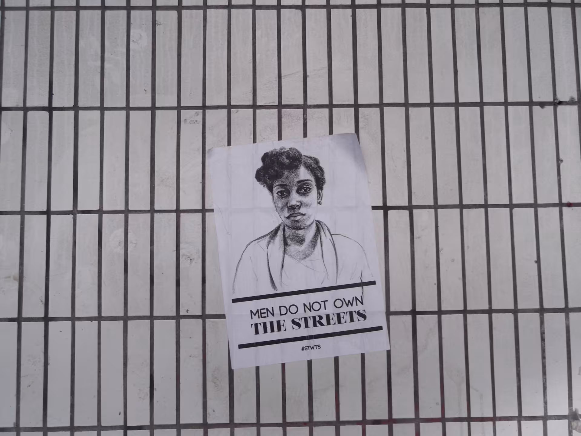 Plakat an einem Zaun mit der Aufschrift "Men do not own the streets"