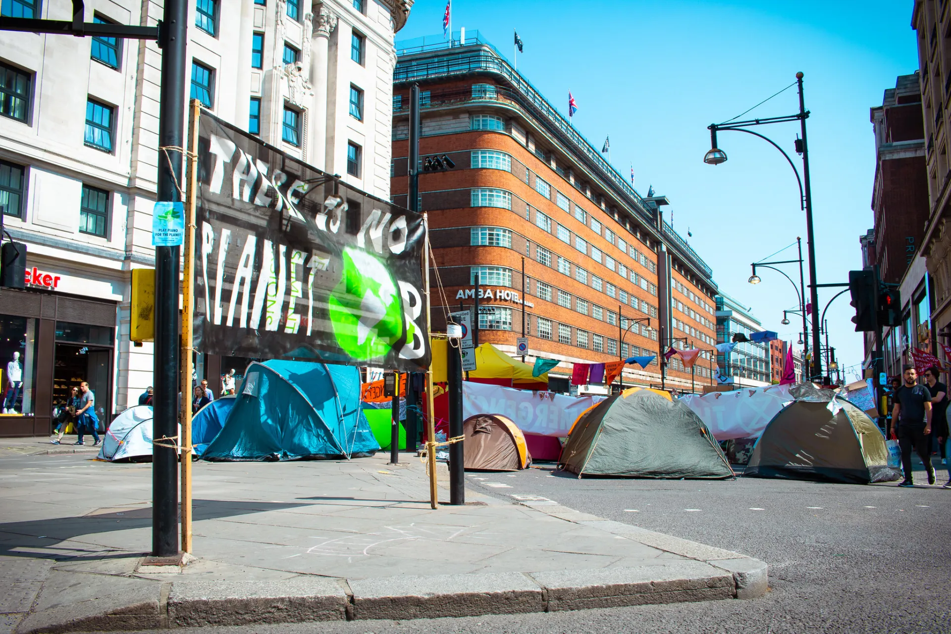 ein Camp mit Zelten an einer Straßenkreuzung, im Vordergrund ein Banner mit der Aufschrift There is no planet B