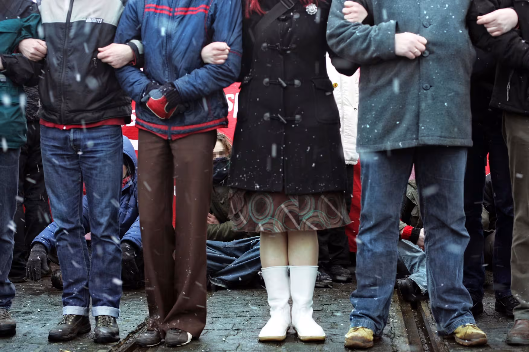 Menschen stehen Arm in Arm in einer Kette vor einer Sitzblockade