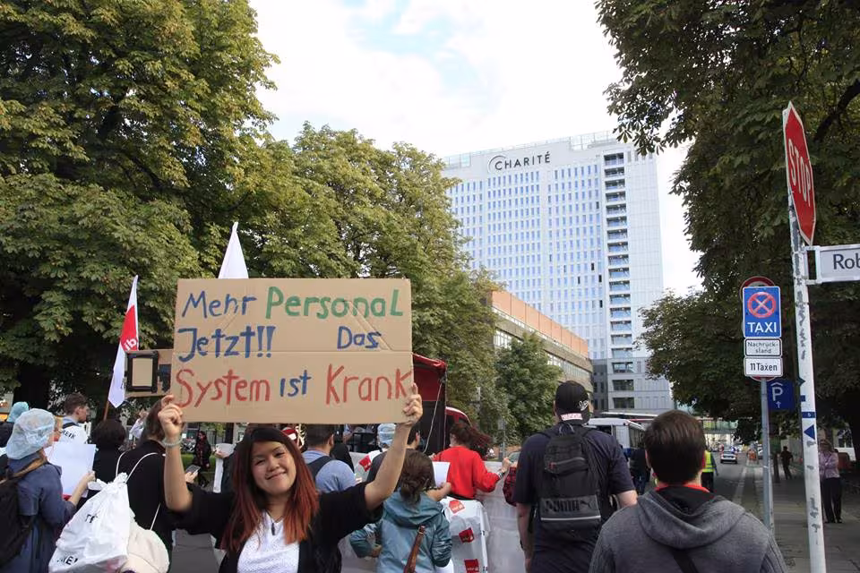 Demonstrantin hält ein Schild mit der Aufschrift Mehr Personal jetzt!! Das System ist krank
