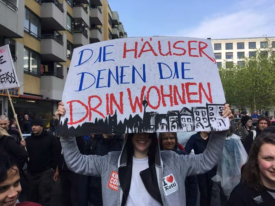 Demonstrant*in hält ein Schild mit der Aufschrift "Die Häuser denen, die drin wohnen"