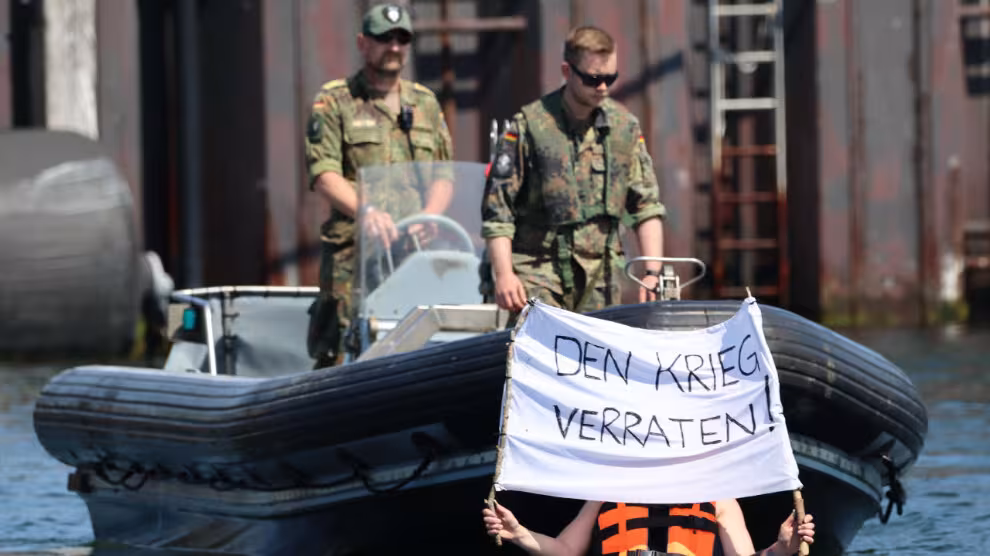 Bundeswehr rubber Boot davor Person in Kanu mit Schild: Den Krieg verraten