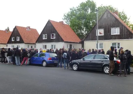 Bild von blockierter Abschiebung. Menschen sehen neben Autos auf Bürgersteig