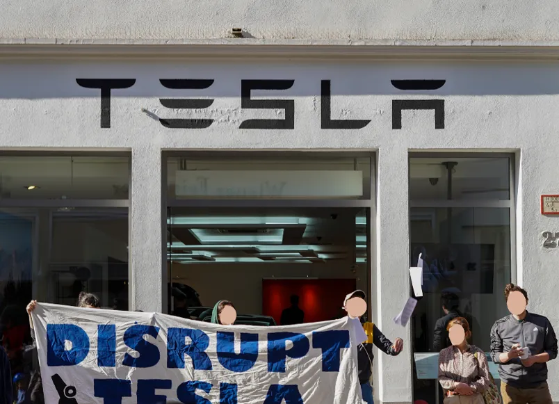 Aktivistinnen vor Tesla Geschäft mit Disrupt Tesla Banner