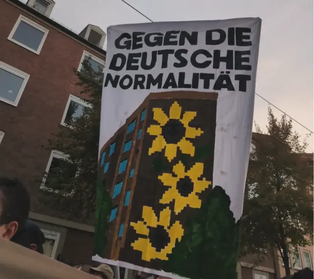 Hochbanner Gegen die deutsche Normalität. Zeichnung des Sonnenblumenhauses.