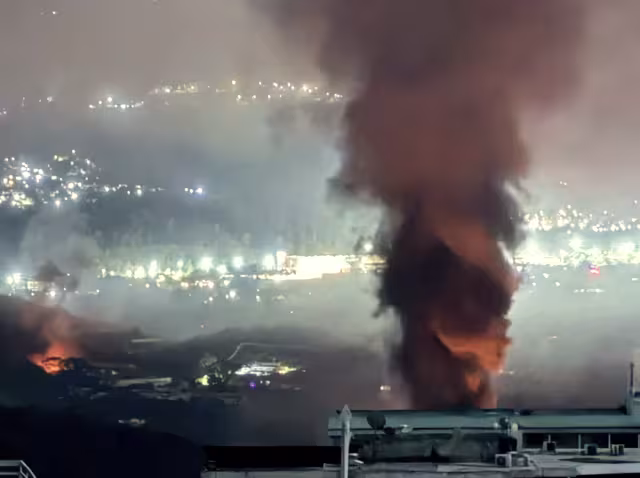 große Rauchwolke vor den Lichtern einer Stadt