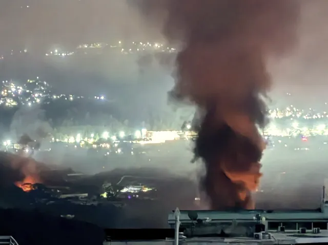 große Rauchwolke vor den Lichtern einer Stadt
