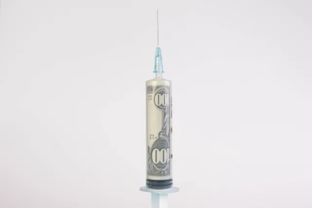 eine Spritze, aufgezogen mit einem 100 Dollar Schein