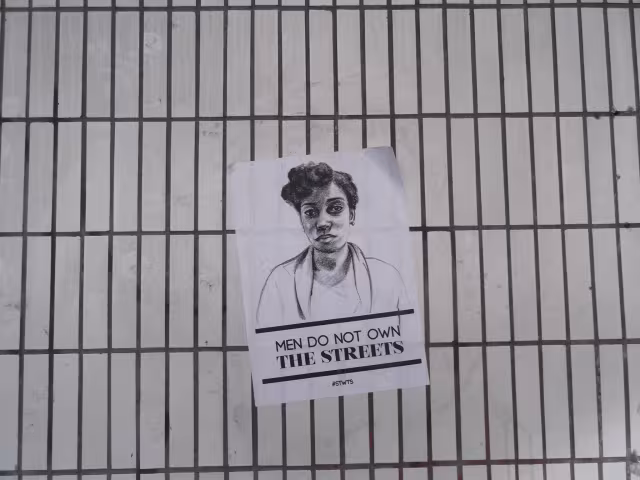 Plakat an einem Zaun mit der Aufschrift "Men do not own the streets"