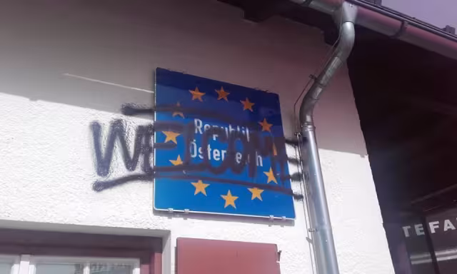 Schild mit Europaflagge darüber ein Grafitti "Welcome"