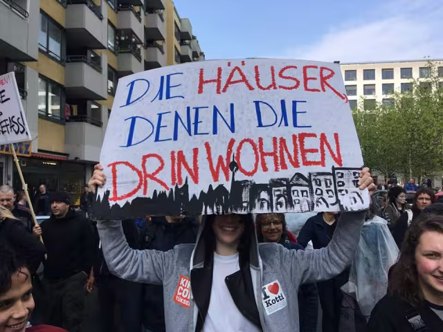 Demonstrant*in hält ein Schild mit der Aufschrift "Die Häuser denen, die drin wohnen"
