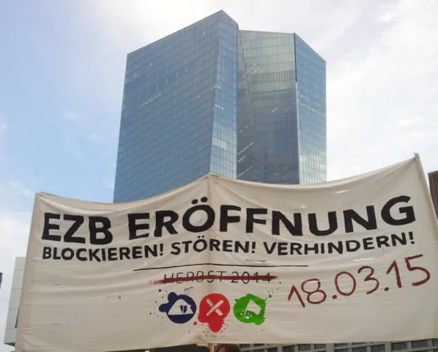 Hochhaus (EZB) im Hintergrund davor Banner: EZB Eröffnung Blockieren! Stören! Verhindern!