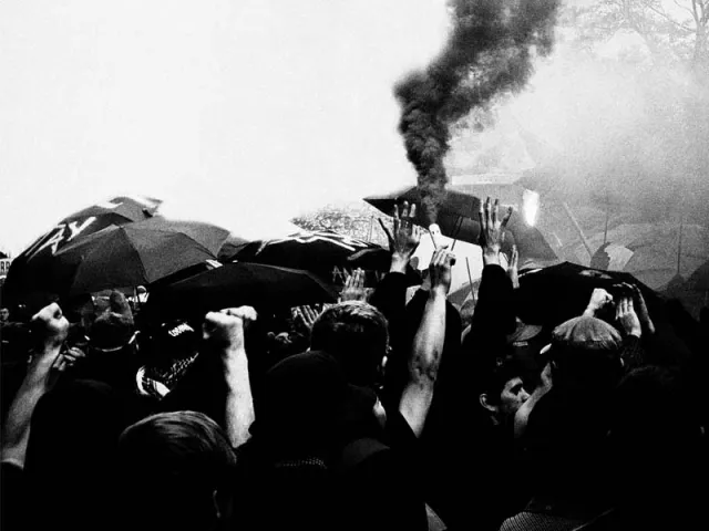 Schwarz weiß Demo, rauch und regenschirme in der Menge